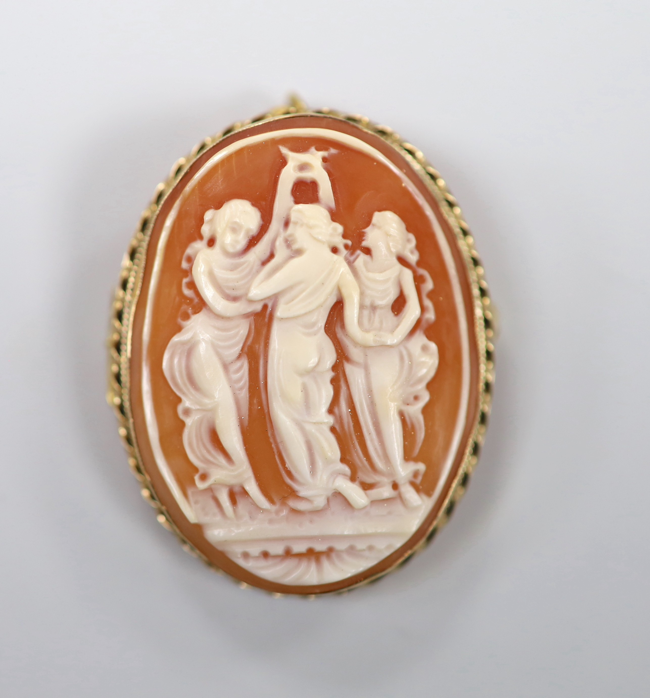 A modern 9ct gold mounted oval cameo shell pendant brooch, carved with The Three Graces, 41mm, gross weight 10.8 grams.